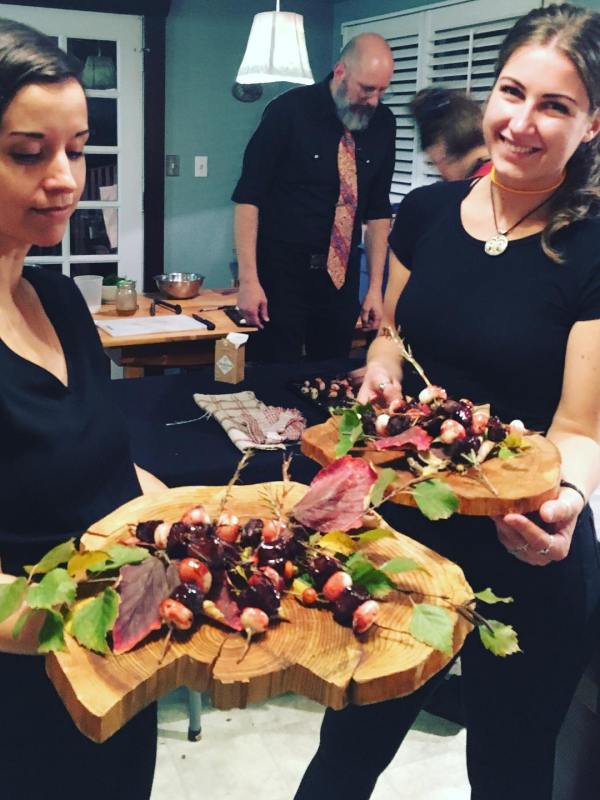 a group of people standing around a table with food